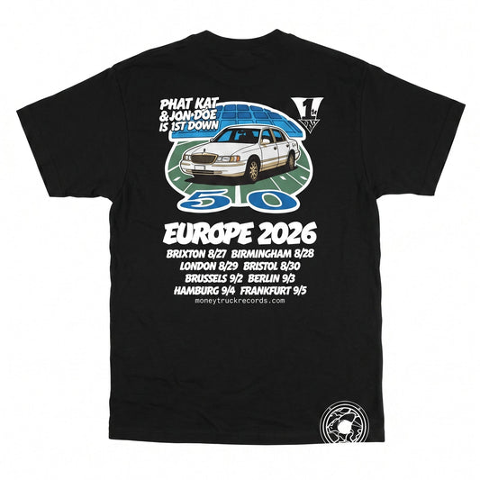 A black short-sleeve graphic t-shirt laid flat against a white background. The shirt features a large front print with a white car, a blue circular design, and text celebrating 'Phat Kat & Ron Doe Is St Down Europe 2026' along with multiple city names and 'Money Truck Records'.